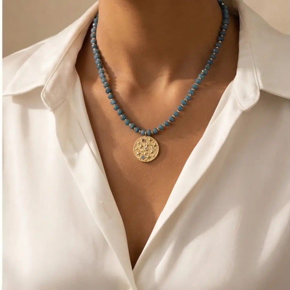 Woman wearing Blue Amethyst Beaded Necklace with Gold Celestial Medallion pendant, elegant celestial gemstone necklace.
